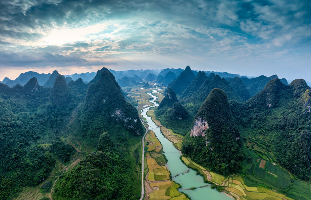 Panorama aerial view of Phong Nam Valley with rice field and winding river flows through traditional village in countryside at Cao Bang, Vietnam